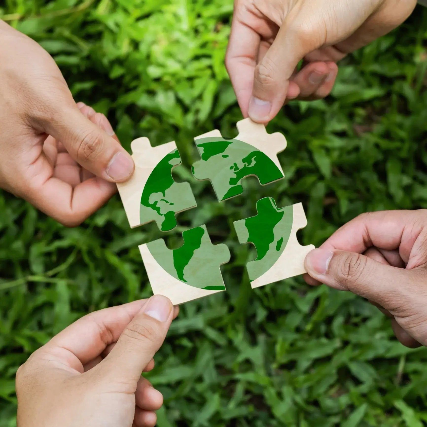 Hands putting together green puzzle pieces