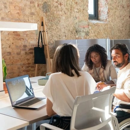 group of coworkers seated at desk working on a laptop