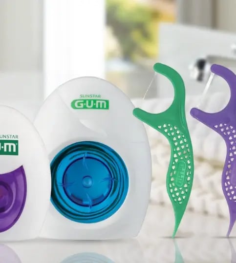 GUM dental floss picks and floss dispenser close-up with ergonomic handles, strong floss thread, and oral care products for teeth cleaning and gum health.
