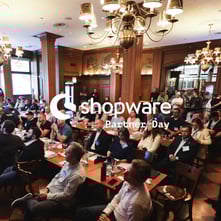 Board room filled with executives at Shopware event covered by the white Shopware Partner Day logo