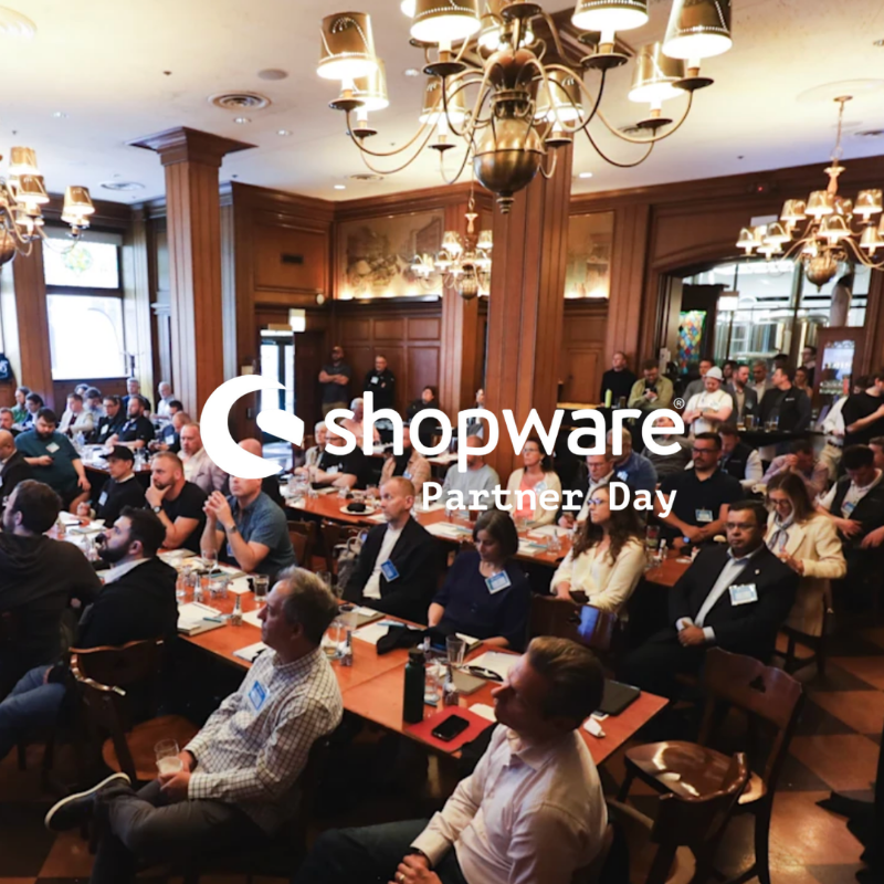 Board room filled with executives at Shopware event covered by the white Shopware Partner Day logo