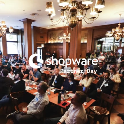 Board room filled with executives at Shopware event covered by the white Shopware Partner Day logo