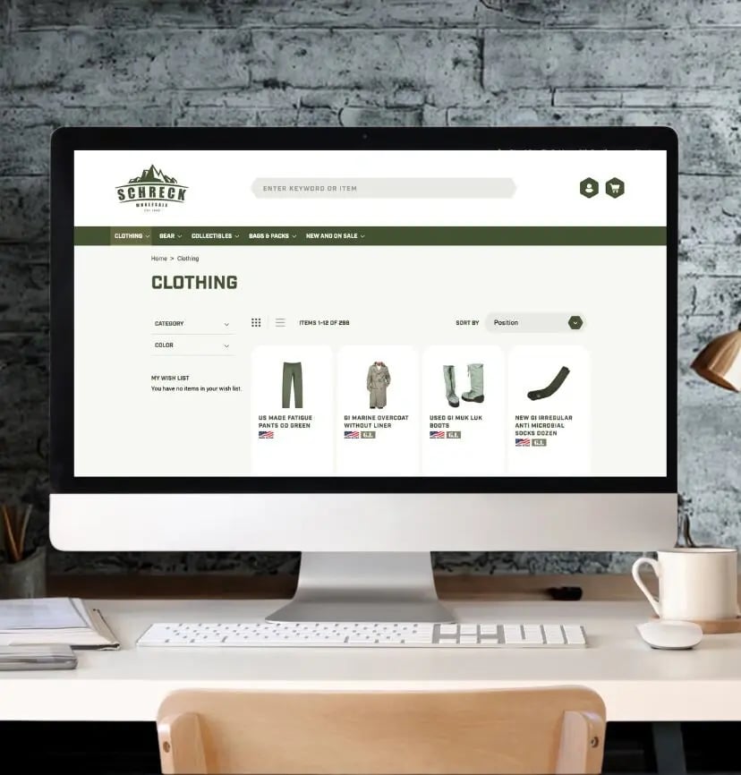 Desktop computer displaying eCommerce clothing website with product listings, minimalist workspace setup, online retail shopping interface for apparel and fashion store