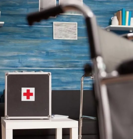 First aid kit in a modern living room with blue textured wall, emergency medical box with green cross symbol on white table, home safety preparedness concept-2