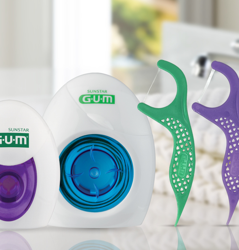 GUM dental floss picks and floss dispenser close-up with ergonomic handles, strong floss thread, and oral care products for teeth cleaning and gum health.